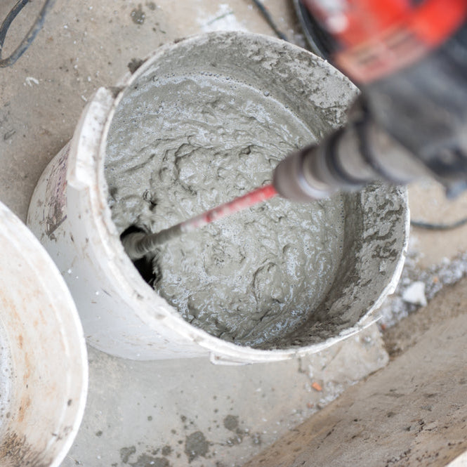 Mixing concrete with a handheld concrete mixer.