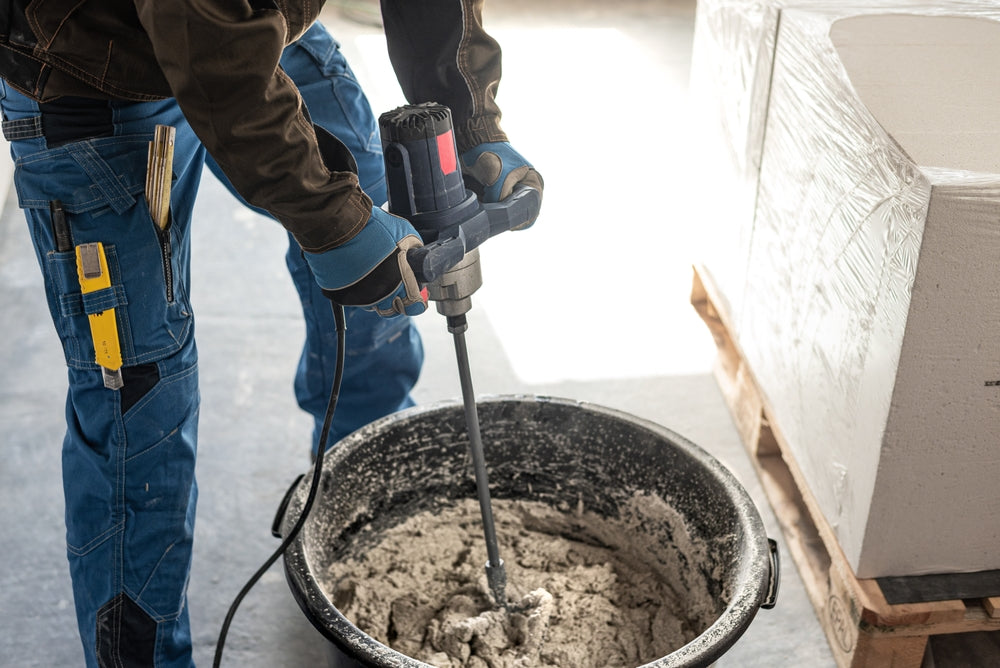 Mixing mortar using a handheld material mixer in the mortar bin.