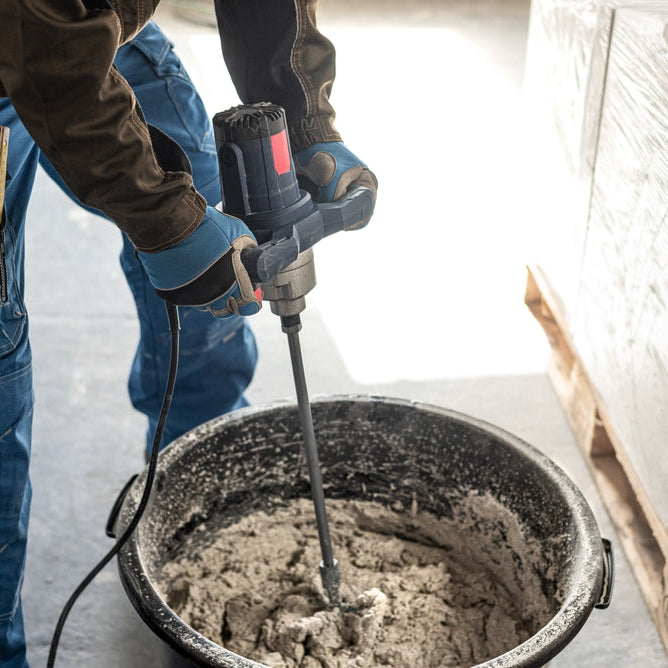 Mixing mortar using a handheld material mixer in the mortar bin.