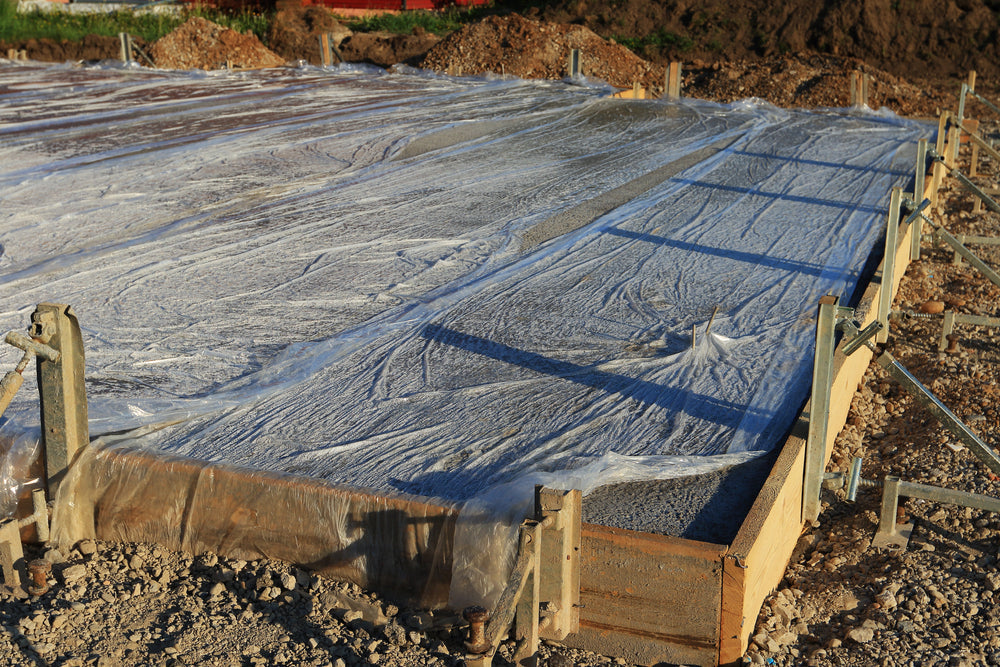 Base plate freshly concreted. To keep the fresh concrete moist, it is covered with foil. Sunlight. Newly built with formwork.