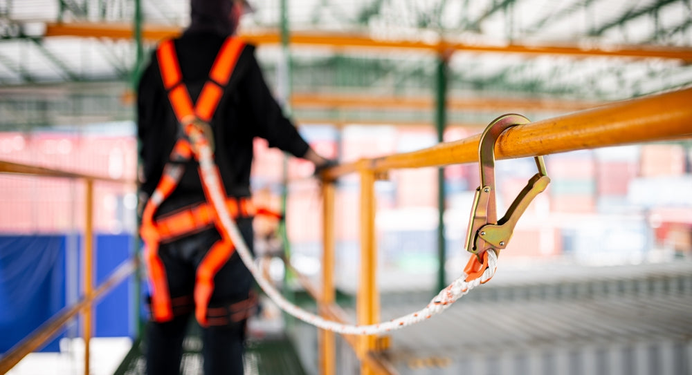 Construction worker practicing scaffolding safety wearing a harness.