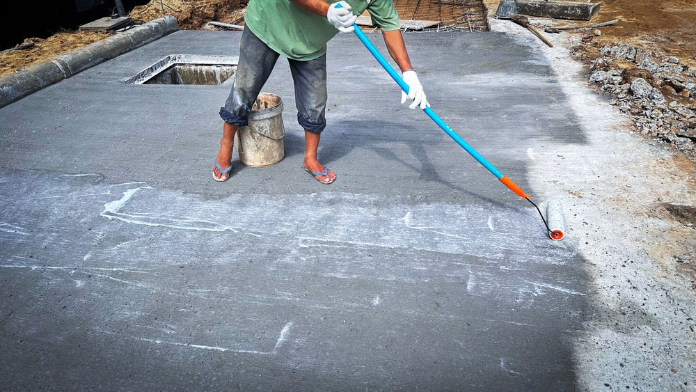 Technician applies concrete curing agent to prevent cracking. concrete primer Steps for applying foundation with a roller on concrete floors Primer for strengthening the surface.