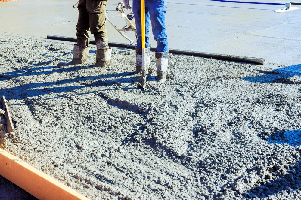 Construction workers pouring concrete to foundation at residential site on works day for building