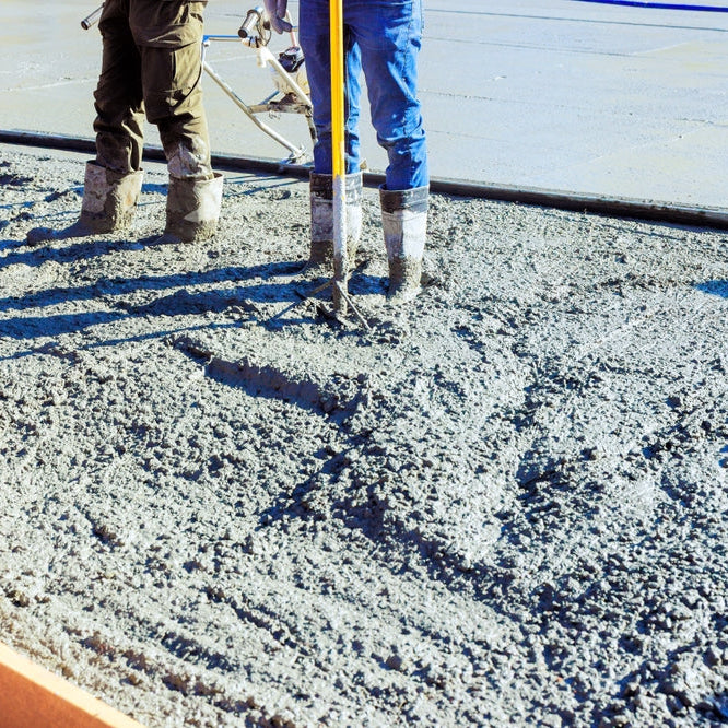 Construction workers pouring concrete to foundation at residential site on works day for building